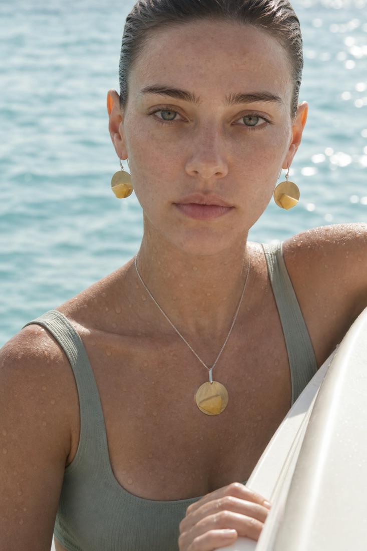 Model by the sea wearing Helia earrings and pendant